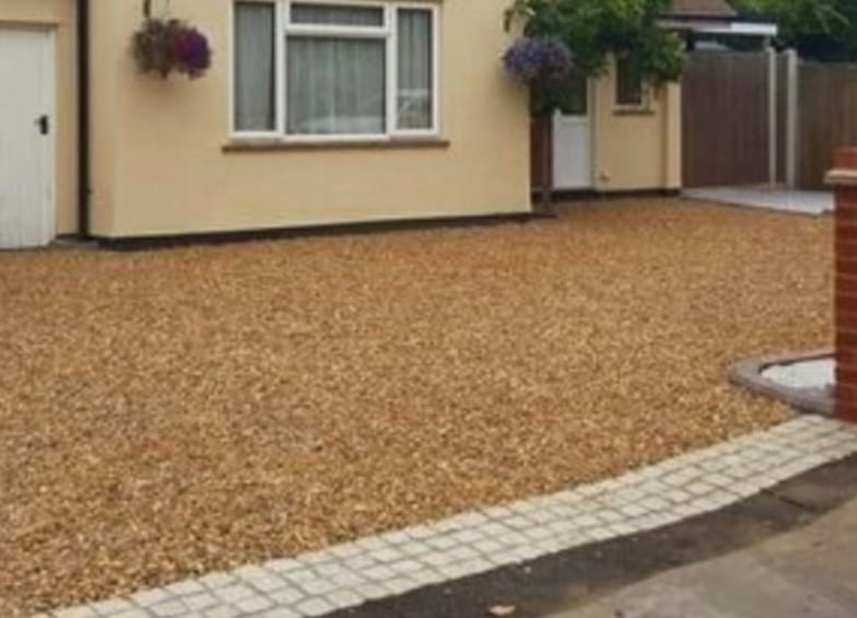 Gravel driveway with cobblestone edging at front of bungalow