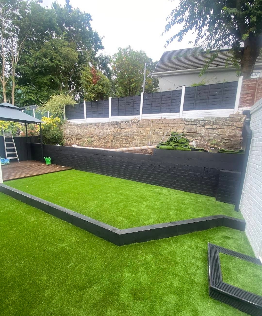 Tiered garden with artificial grass, dark timber sleepers and decking