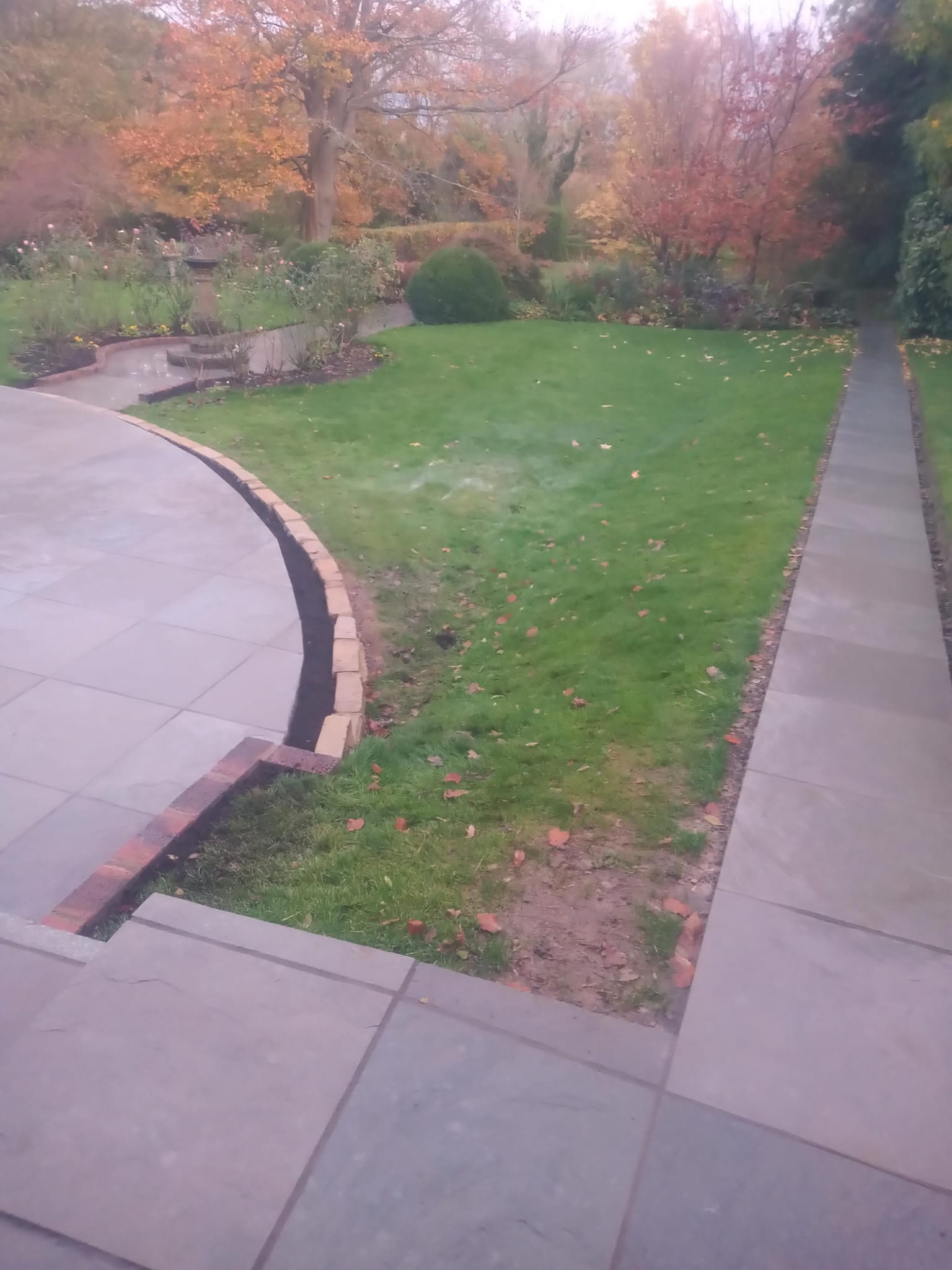 Formal garden pathway with brick edging and sundial feature
