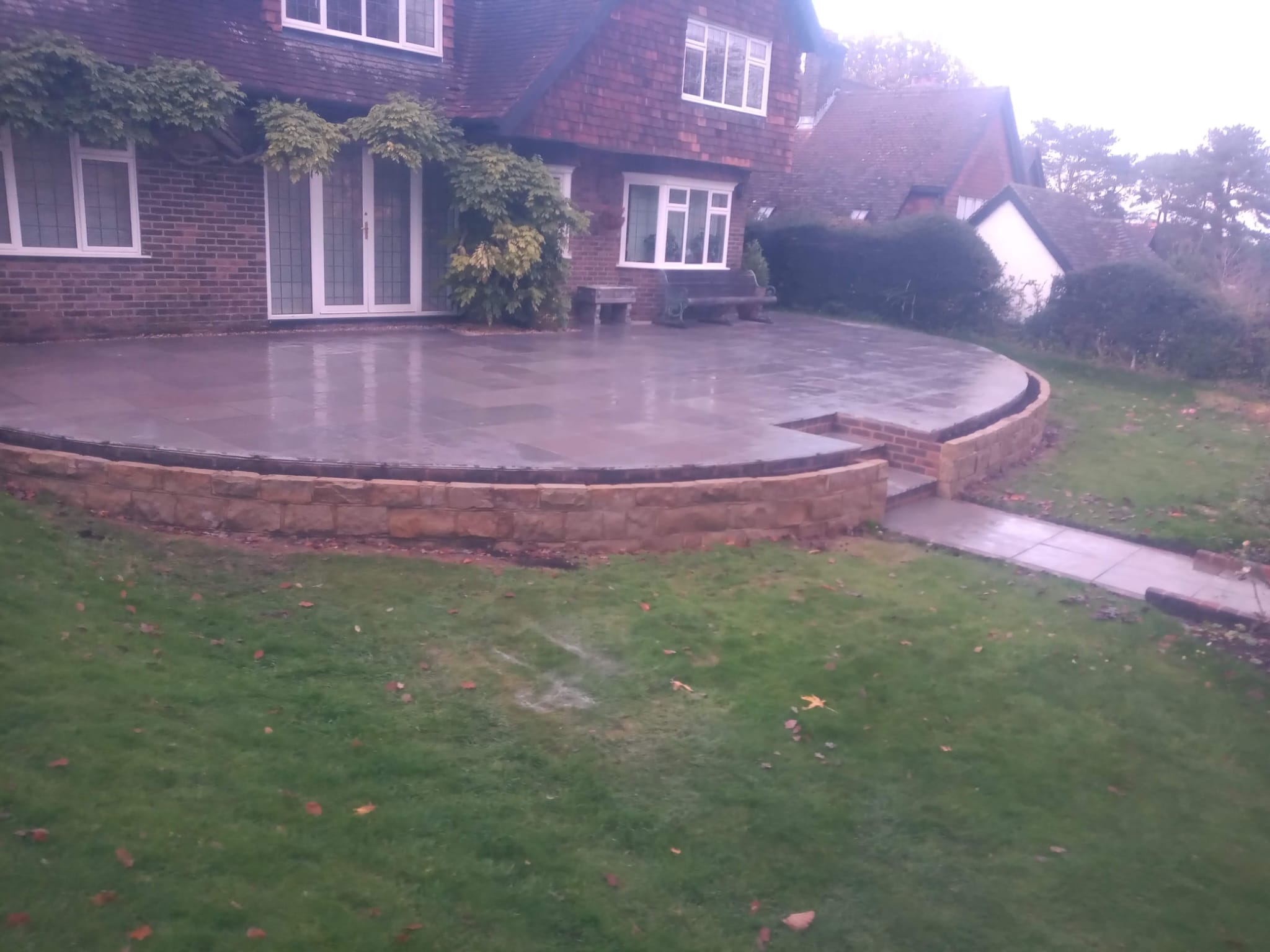 Curved raised patio with stone retaining wall in East Sussex