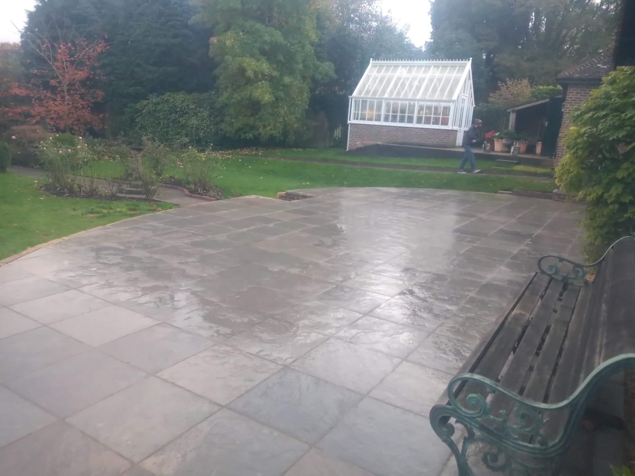 Large natural stone patio overlooking garden with greenhouse
