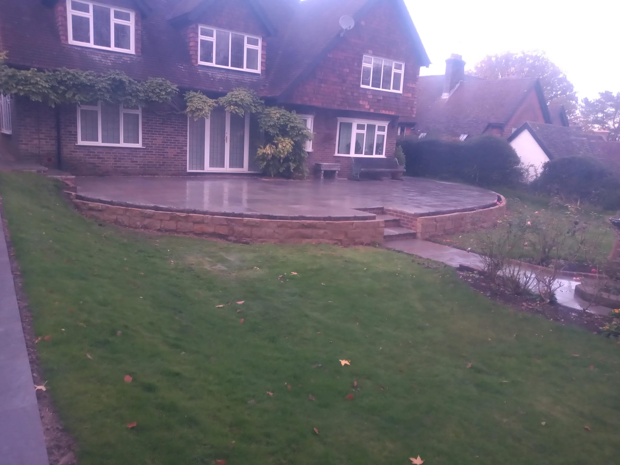 Raised curved patio with stone retaining wall on traditional home