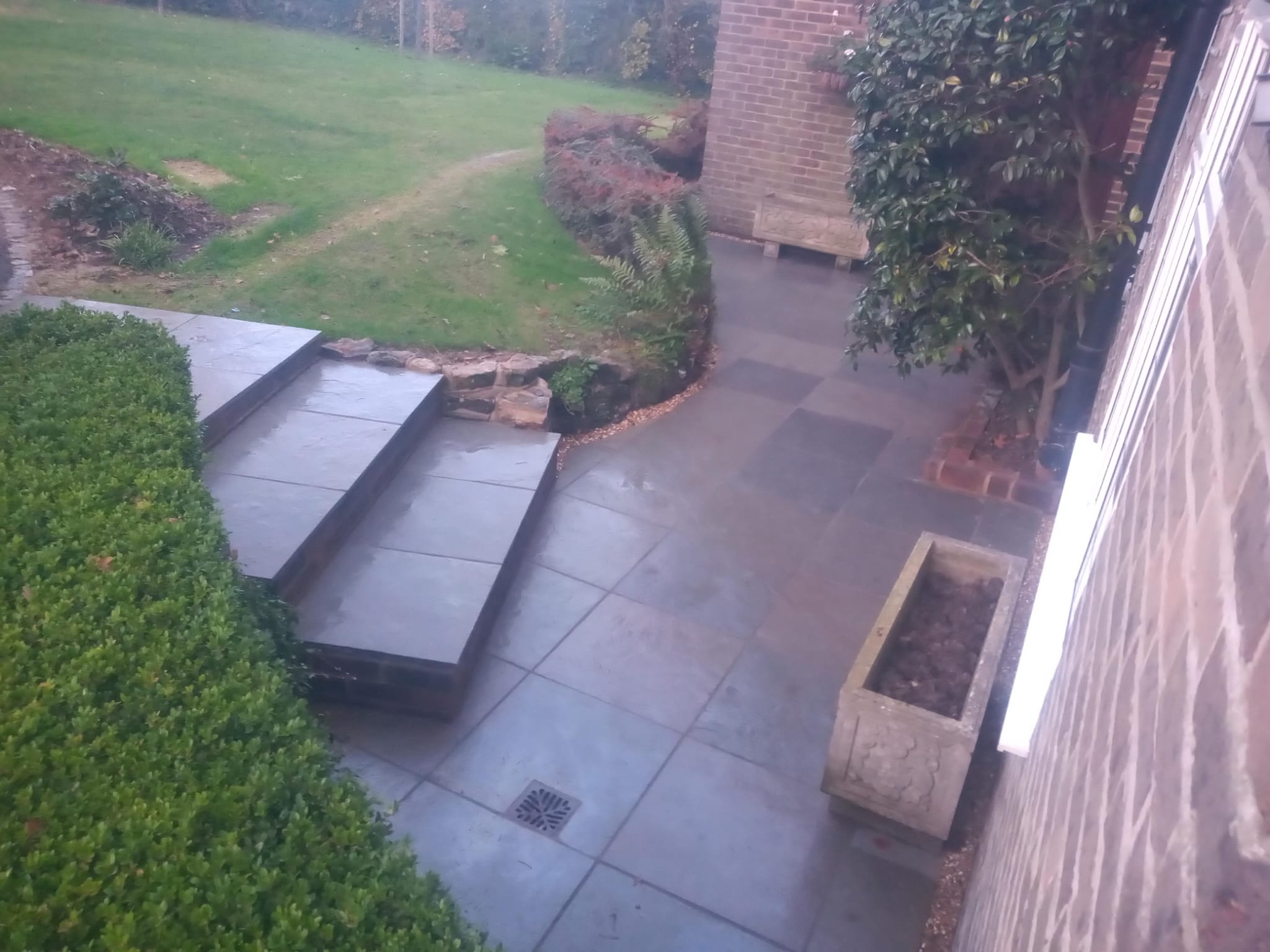 Slate patio with curved timber sleeper steps to lawn